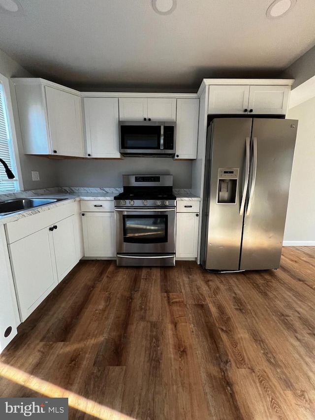 kitchen with white cabinets, dark wood-type flooring, and appliances with stainless steel finishes