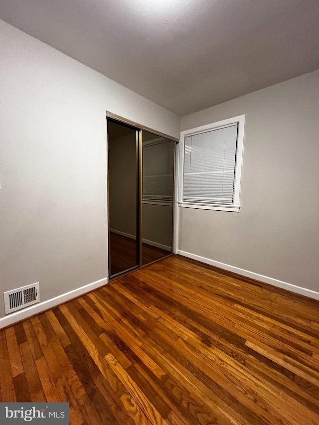 unfurnished bedroom featuring wood-type flooring and a closet