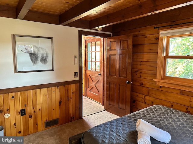 carpeted bedroom with beamed ceiling, wood ceiling, and wood walls