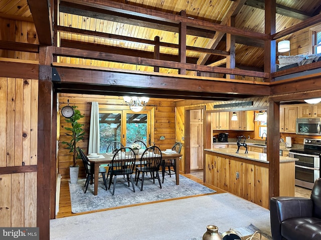 dining space featuring wooden walls, light colored carpet, and a notable chandelier