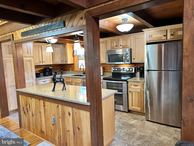 kitchen with light stone countertops, stainless steel appliances, sink, beam ceiling, and wood walls