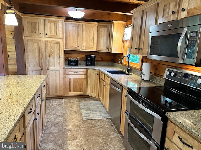 kitchen with appliances with stainless steel finishes, light stone counters, hanging light fixtures, and sink