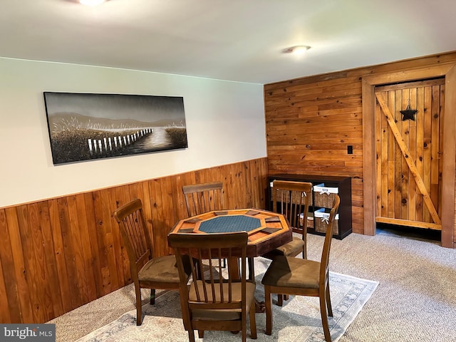 dining area featuring wood walls and light carpet