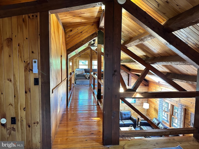 hallway featuring vaulted ceiling with beams, wood walls, and wood ceiling