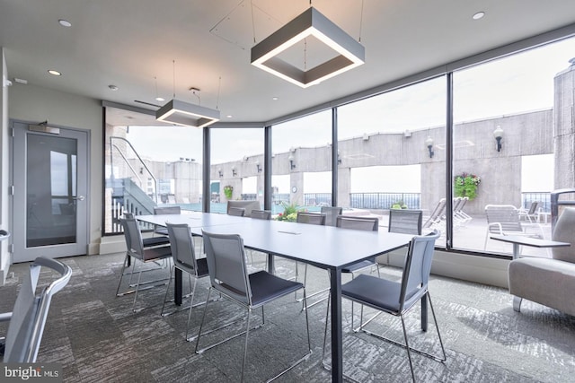 dining room with dark colored carpet, a healthy amount of sunlight, and floor to ceiling windows