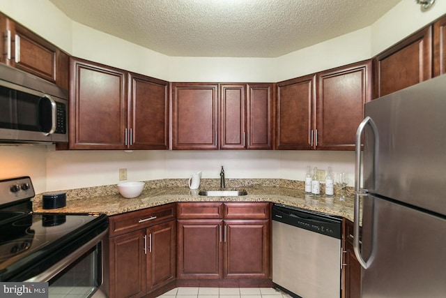 kitchen with light stone countertops, appliances with stainless steel finishes, a textured ceiling, and sink