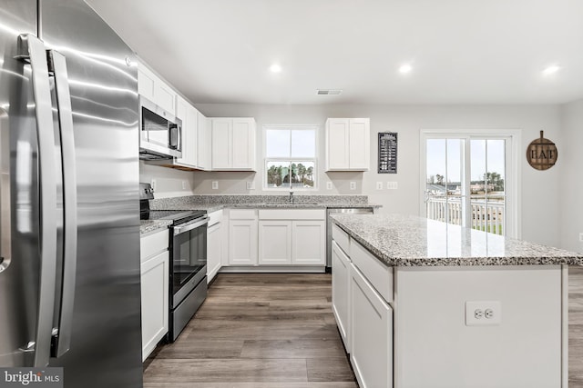 kitchen with a center island, stainless steel appliances, white cabinetry, and a wealth of natural light