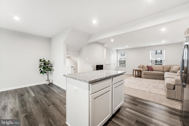 kitchen featuring white cabinets, dark hardwood / wood-style flooring, a center island, and light stone countertops