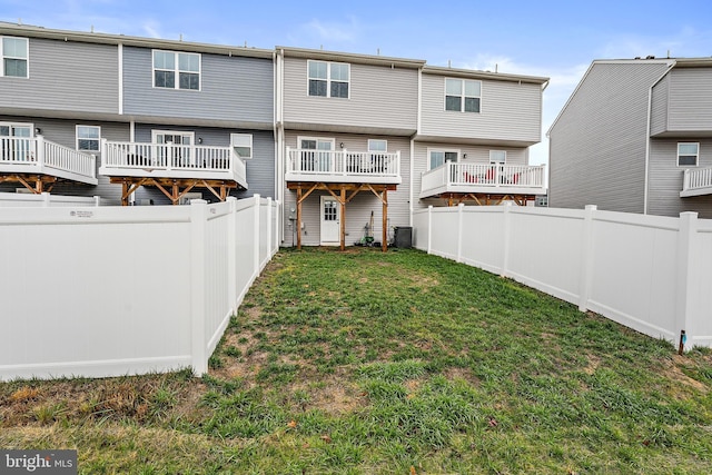 rear view of property with central air condition unit and a yard