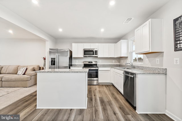 kitchen featuring sink, appliances with stainless steel finishes, a kitchen island, dark hardwood / wood-style flooring, and white cabinetry