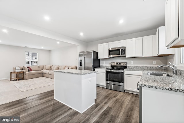 kitchen with appliances with stainless steel finishes, dark hardwood / wood-style flooring, sink, a center island, and white cabinetry