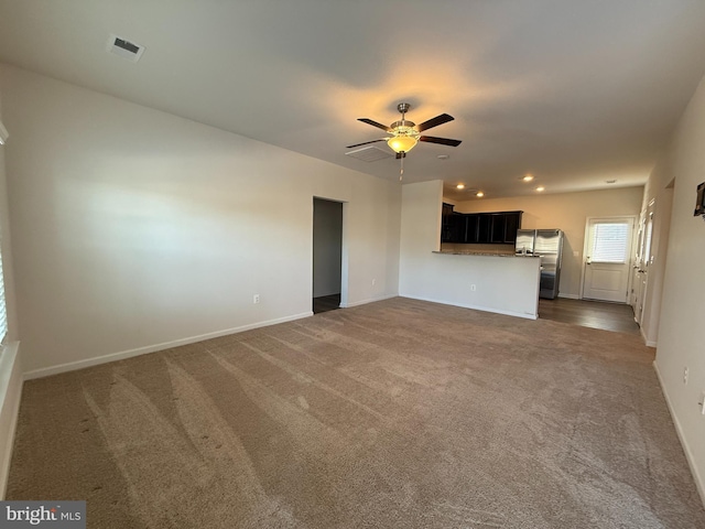 unfurnished living room featuring ceiling fan and dark carpet