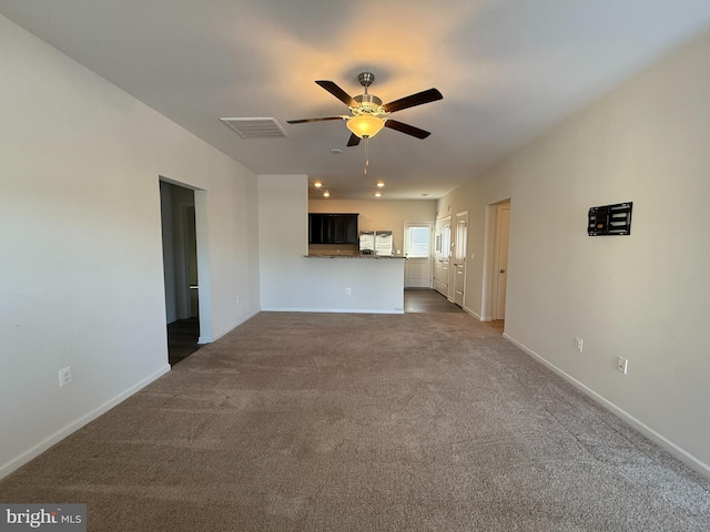 unfurnished living room featuring ceiling fan and dark carpet