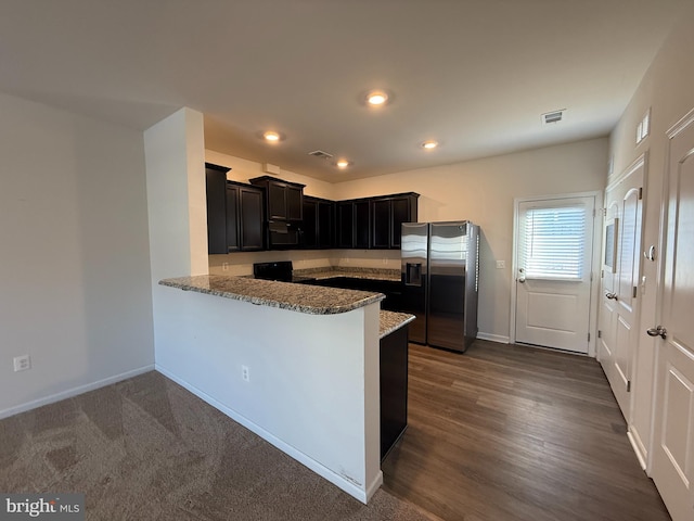 kitchen featuring kitchen peninsula, stainless steel refrigerator with ice dispenser, stove, and light stone counters