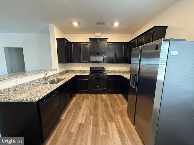 kitchen featuring light stone countertops, kitchen peninsula, light wood-type flooring, sink, and black appliances