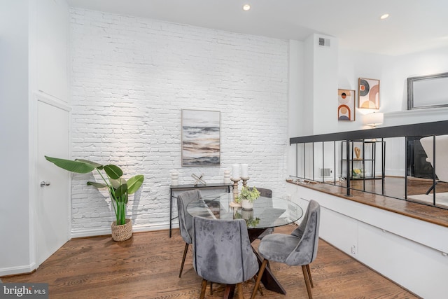 dining room with dark hardwood / wood-style floors and brick wall