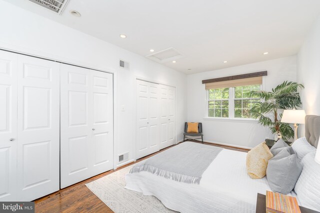 bedroom with multiple closets and dark hardwood / wood-style floors