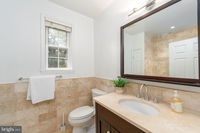 bathroom featuring tile walls, vanity, and toilet