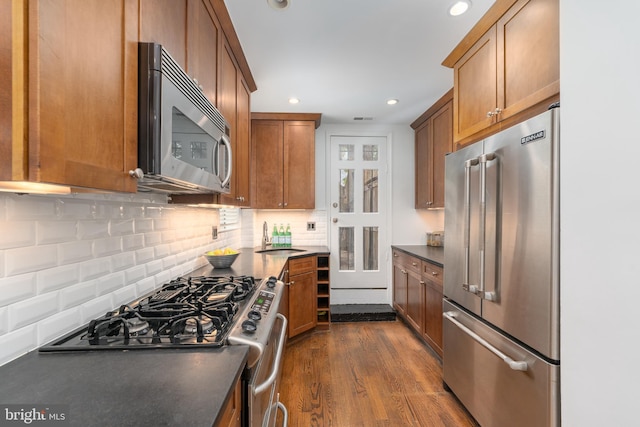 kitchen with sink, decorative backsplash, dark wood-type flooring, and appliances with stainless steel finishes