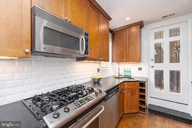 kitchen featuring dark wood-type flooring, appliances with stainless steel finishes, sink, and backsplash