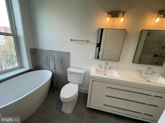 bathroom with a tub to relax in, tile patterned flooring, vanity, and toilet