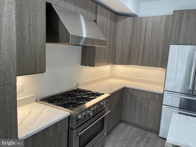 kitchen with light stone counters, wall chimney range hood, and stainless steel appliances