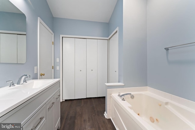 bathroom featuring hardwood / wood-style flooring, a tub to relax in, and vanity