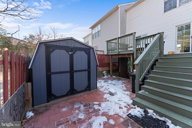 snow covered patio with a deck and a storage unit