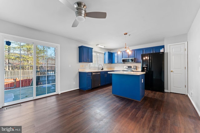 kitchen featuring appliances with stainless steel finishes, hanging light fixtures, dark hardwood / wood-style floors, a center island, and blue cabinets