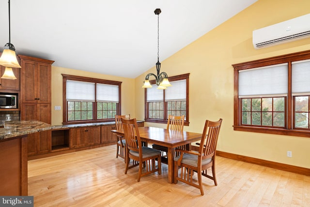 dining area featuring a chandelier, light wood-type flooring, a wall unit AC, and lofted ceiling