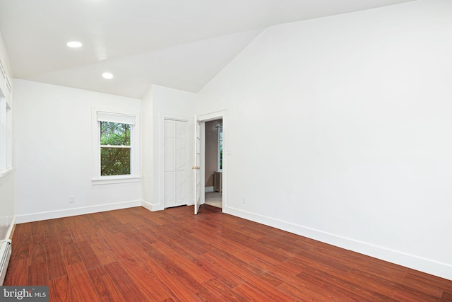 spare room featuring hardwood / wood-style flooring, vaulted ceiling, and baseboard heating