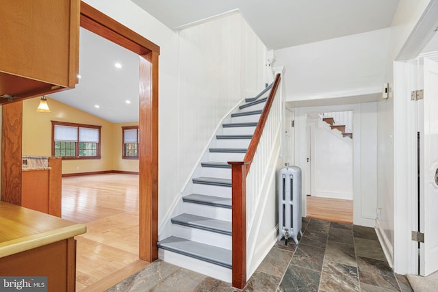 stairs featuring radiator heating unit, vaulted ceiling, and hardwood / wood-style floors