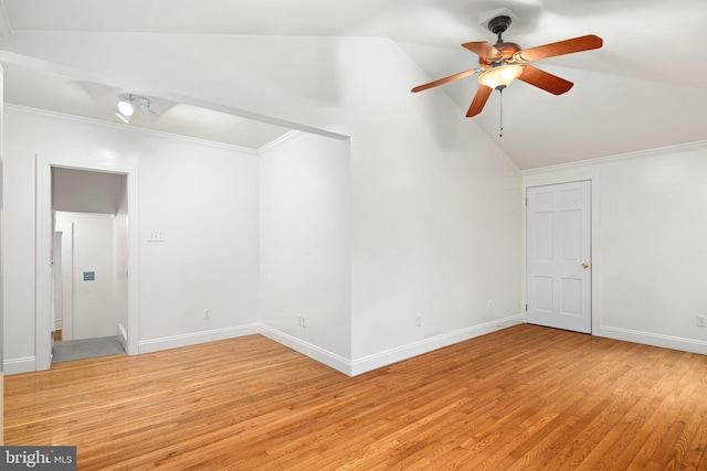 empty room featuring light wood-type flooring, vaulted ceiling, ceiling fan, and crown molding