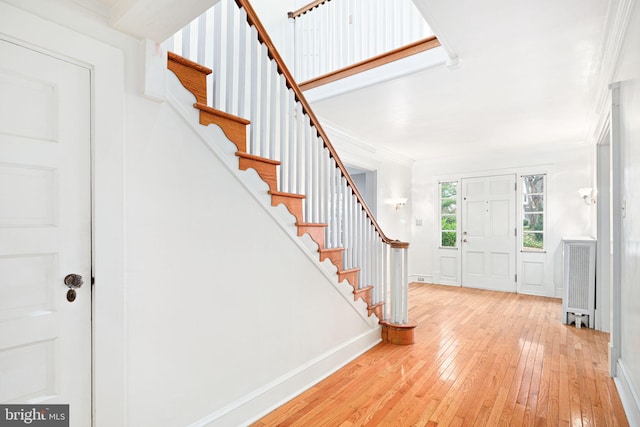 foyer with light hardwood / wood-style floors, ornamental molding, and radiator heating unit