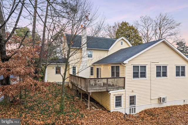 back house at dusk featuring a deck