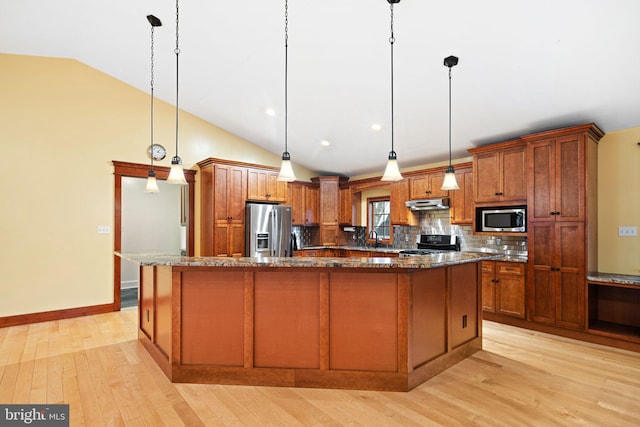 kitchen featuring appliances with stainless steel finishes, decorative light fixtures, a kitchen island, and lofted ceiling