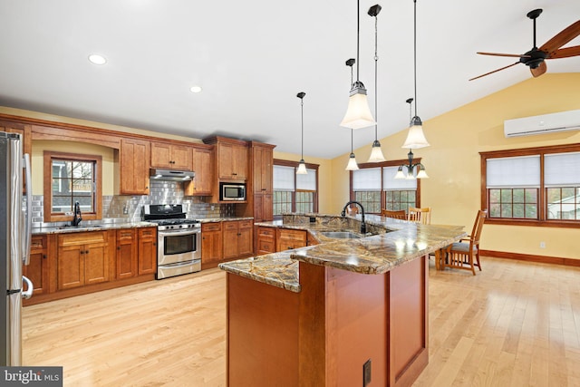 kitchen featuring sink, vaulted ceiling, decorative light fixtures, appliances with stainless steel finishes, and light wood-type flooring