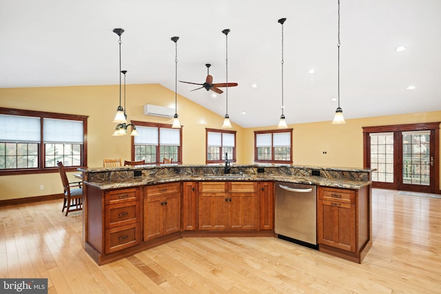 kitchen with an AC wall unit, dishwasher, light hardwood / wood-style floors, hanging light fixtures, and an island with sink