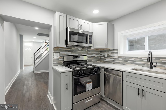 kitchen with light stone counters, dark hardwood / wood-style floors, stainless steel appliances, decorative backsplash, and sink