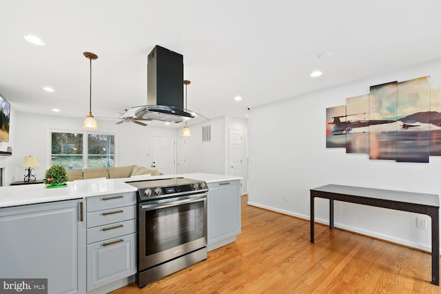 kitchen with stainless steel range with electric cooktop, hanging light fixtures, ceiling fan, gray cabinets, and island range hood