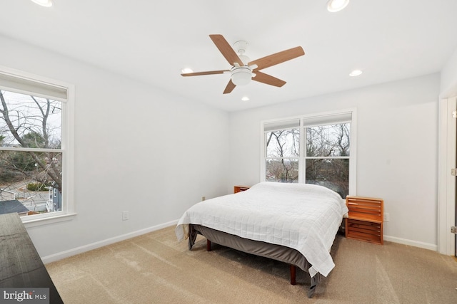 bedroom with multiple windows, ceiling fan, and light colored carpet