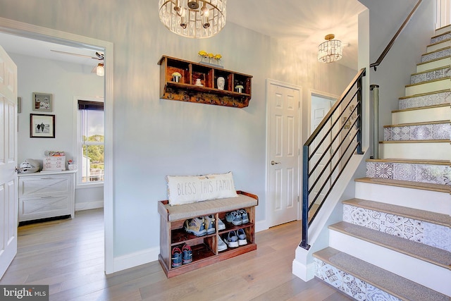 stairway featuring wood-type flooring and ceiling fan with notable chandelier