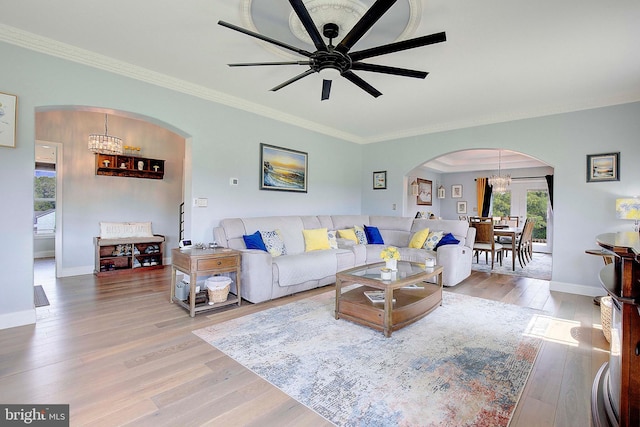 living room with hardwood / wood-style floors, ceiling fan with notable chandelier, and crown molding