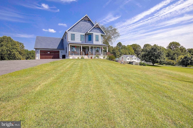 view of front of home with covered porch, a garage, and a front yard