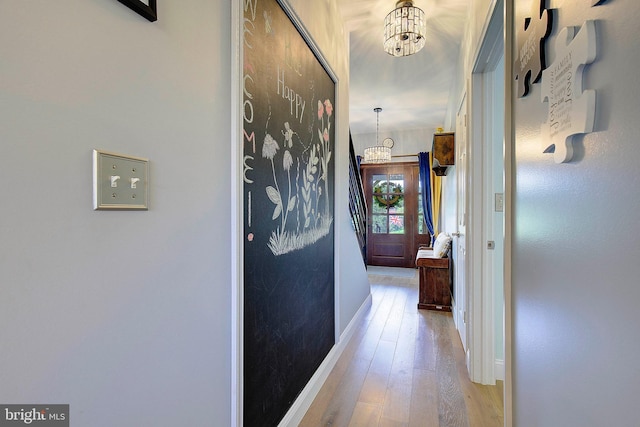 hall with light hardwood / wood-style flooring and a notable chandelier