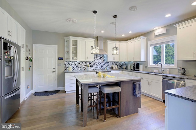 kitchen featuring white cabinets, sink, light hardwood / wood-style flooring, wall chimney exhaust hood, and appliances with stainless steel finishes