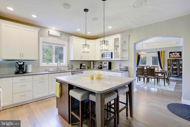 kitchen with a kitchen breakfast bar, light hardwood / wood-style floors, white cabinetry, and appliances with stainless steel finishes