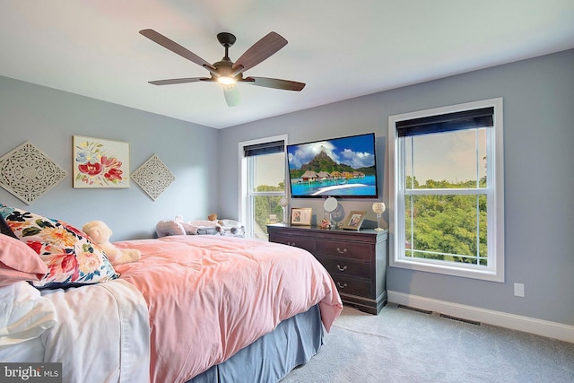 carpeted bedroom with multiple windows and ceiling fan