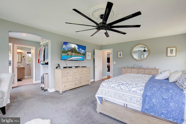 carpeted bedroom featuring a closet, ensuite bathroom, and ceiling fan