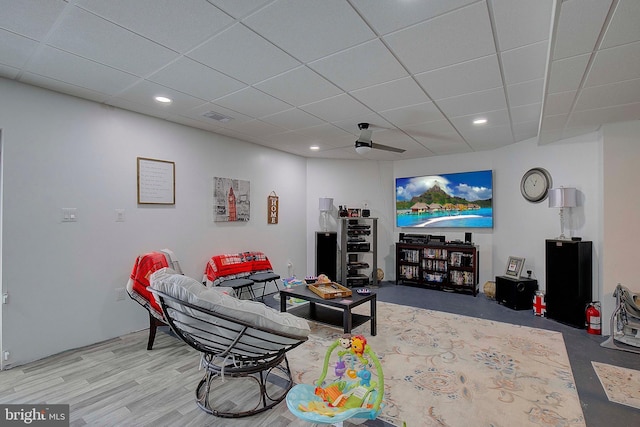 living room with wood-type flooring, a drop ceiling, and ceiling fan